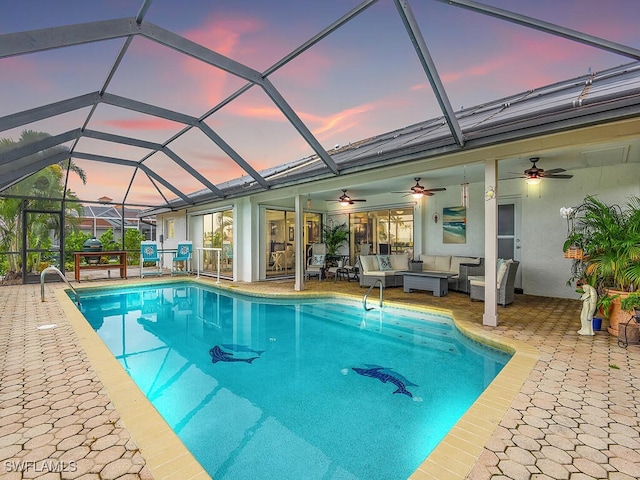 pool at dusk featuring a lanai, an outdoor hangout area, a patio area, and ceiling fan