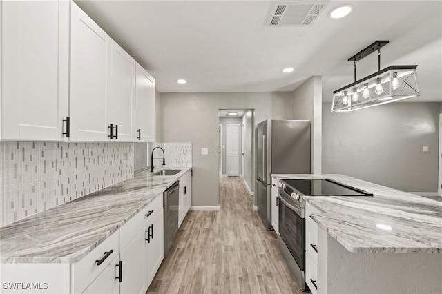 kitchen with appliances with stainless steel finishes, white cabinets, light stone counters, and light wood-type flooring