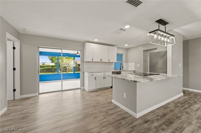 kitchen featuring white cabinetry, light stone countertops, light hardwood / wood-style flooring, and hanging light fixtures