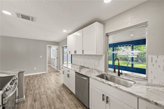 kitchen with white cabinets, light stone countertops, light hardwood / wood-style flooring, sink, and stainless steel appliances