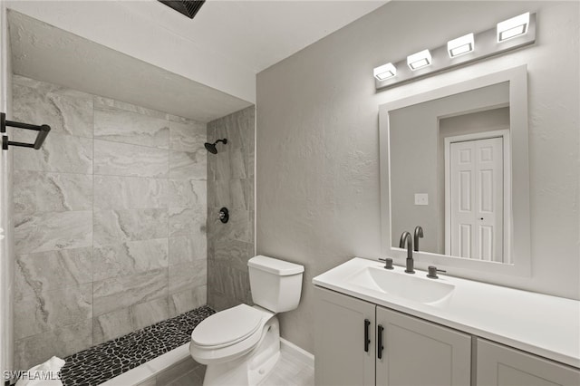 bathroom with vanity, tiled shower, and toilet