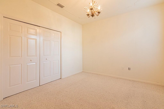 unfurnished bedroom featuring a closet, carpet, and a notable chandelier