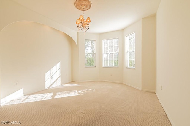 unfurnished room with light colored carpet and an inviting chandelier