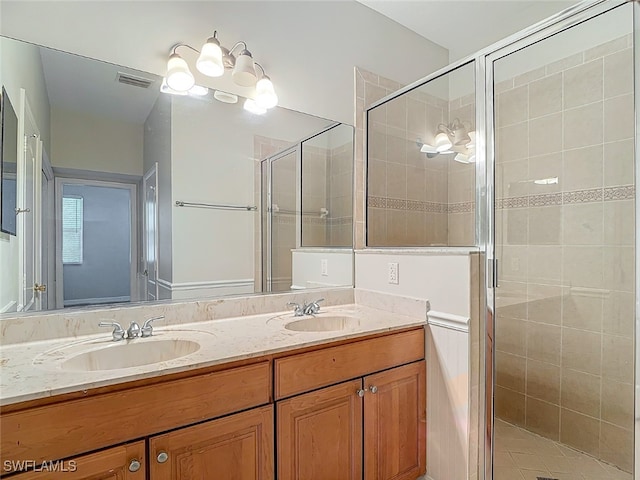 bathroom featuring a shower with door and vanity