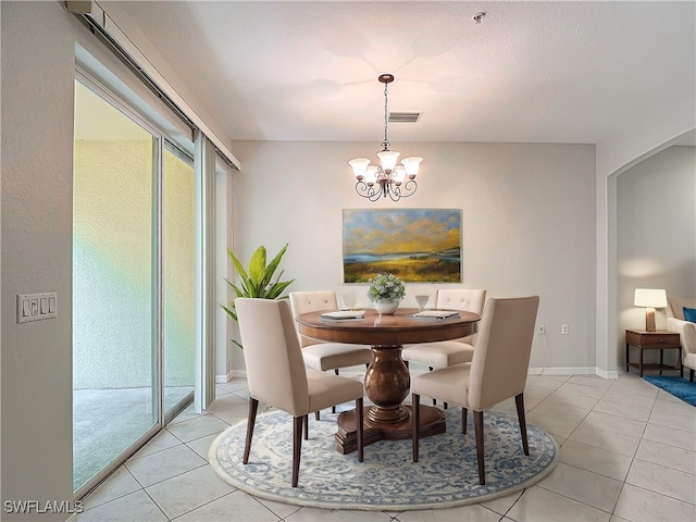 tiled dining room with a textured ceiling and a chandelier