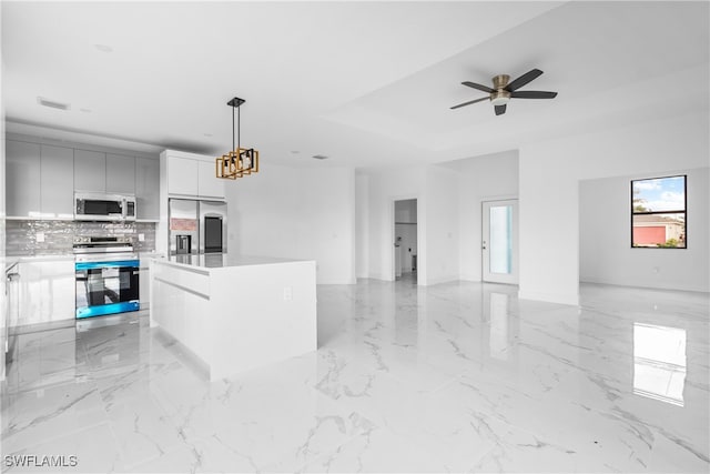 kitchen featuring appliances with stainless steel finishes, backsplash, decorative light fixtures, a kitchen island, and white cabinets