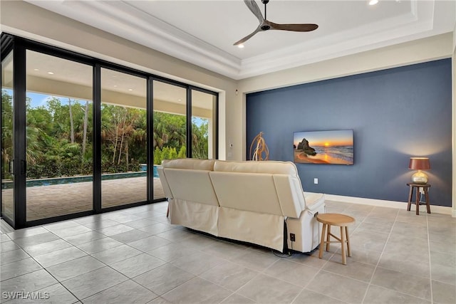 living room featuring light tile patterned floors, a tray ceiling, and ceiling fan