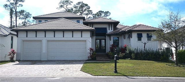 view of front facade with a garage, french doors, and a front lawn