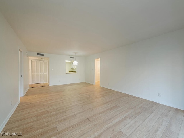 unfurnished room featuring a chandelier and light hardwood / wood-style floors