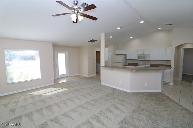 kitchen with white appliances, vaulted ceiling, light colored carpet, and white cabinets