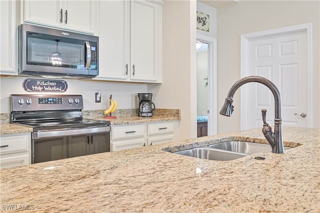 kitchen featuring white cabinetry, stainless steel appliances, sink, and light stone countertops