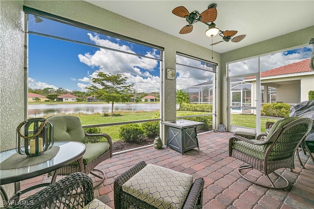 sunroom with ceiling fan and a water view