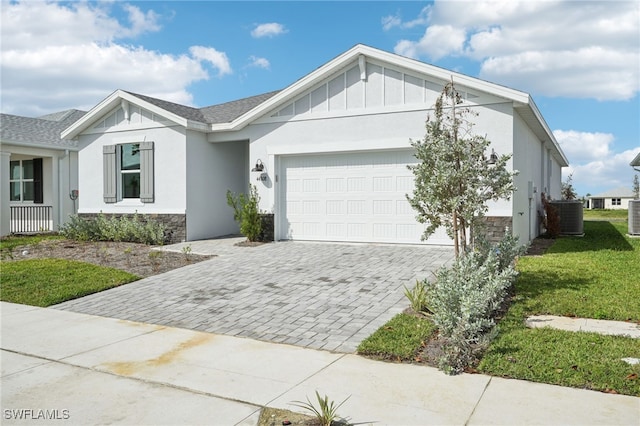 view of front of home with central AC unit, a garage, and a front yard