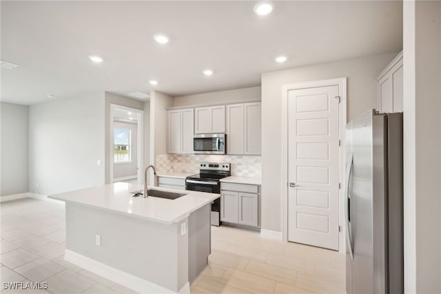 kitchen with a kitchen island with sink, stainless steel appliances, sink, and backsplash