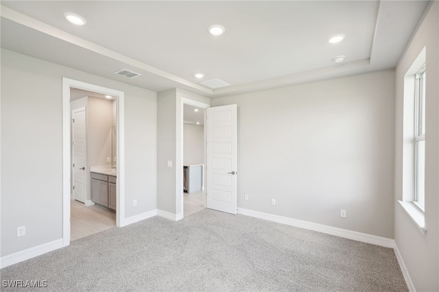 unfurnished bedroom featuring light carpet and connected bathroom