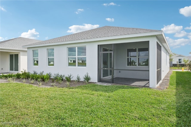 rear view of house featuring a lawn and a sunroom