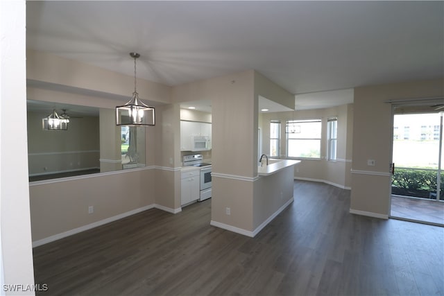 kitchen with white appliances, dark hardwood / wood-style flooring, pendant lighting, white cabinets, and a chandelier