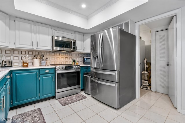 kitchen with light tile patterned floors, appliances with stainless steel finishes, white cabinetry, ornamental molding, and blue cabinets