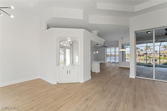 entrance foyer featuring light hardwood / wood-style floors, a towering ceiling, and a tray ceiling