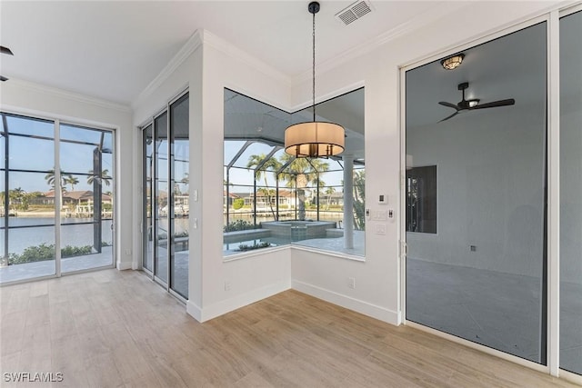 interior space with ceiling fan, hardwood / wood-style floors, crown molding, and a water view