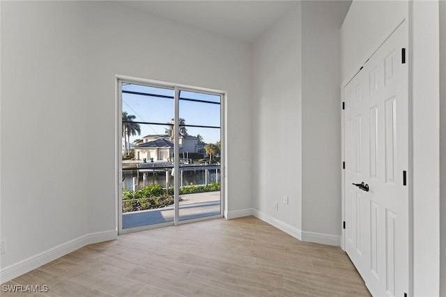 spare room with a water view and light hardwood / wood-style flooring