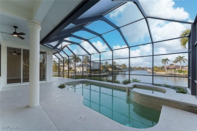 view of pool with glass enclosure, a patio area, a water view, and ceiling fan