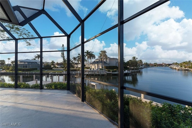 view of patio featuring glass enclosure and a water view