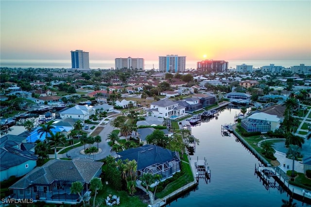 aerial view at dusk featuring a water view