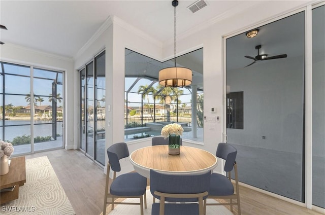 dining space featuring crown molding, light wood-type flooring, and ceiling fan