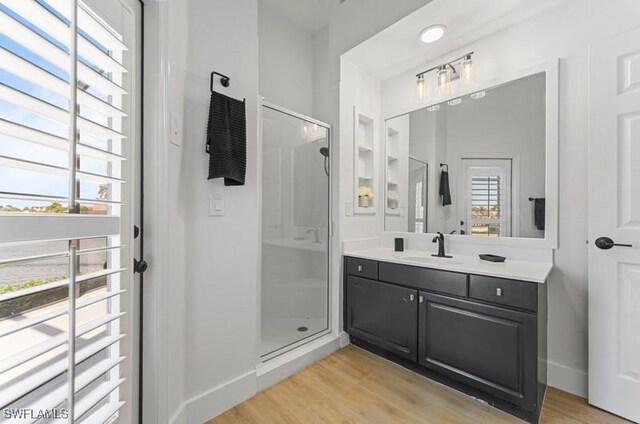 full bath featuring a shower stall, wood finished floors, and vanity