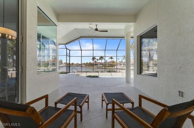 sunroom / solarium with ceiling fan and a water view