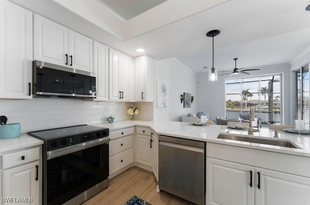 kitchen with light wood-style flooring, a sink, white cabinets, appliances with stainless steel finishes, and tasteful backsplash