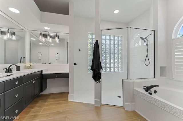 full bath with wood finished floors, walk in shower, a bath, and vanity