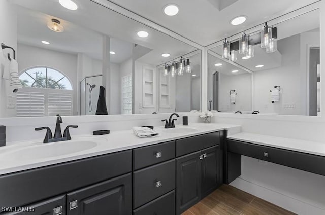 bathroom featuring double vanity, wood finished floors, a sink, and recessed lighting