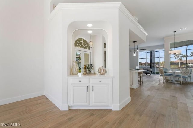 hall featuring ornamental molding, light wood-style flooring, and baseboards