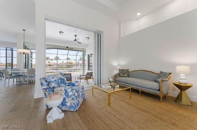 living room featuring plenty of natural light, wood finished floors, a ceiling fan, and baseboards