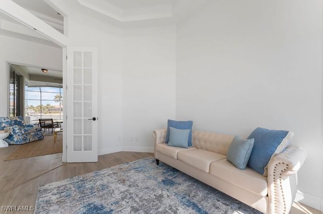 living area with french doors, baseboards, and wood finished floors