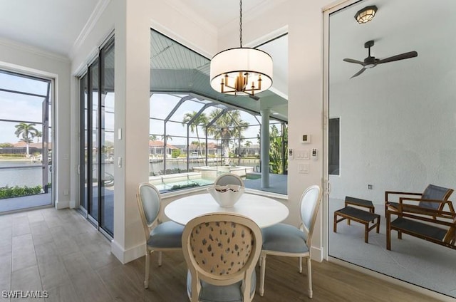 dining room with crown molding, a water view, a sunroom, ceiling fan, and wood finished floors