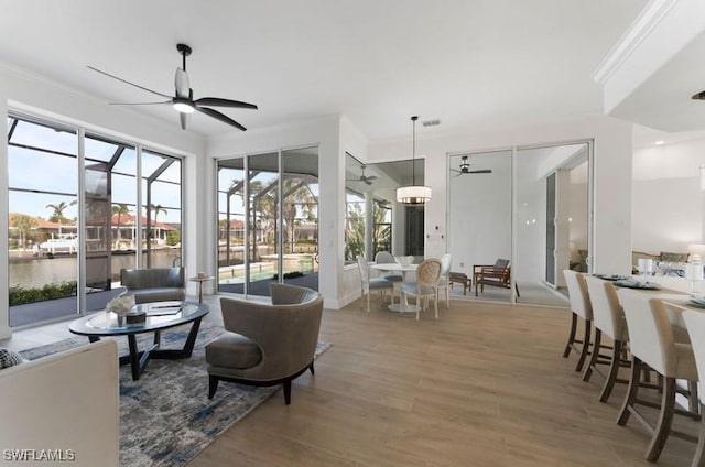 living room featuring a sunroom, wood finished floors, a ceiling fan, and a healthy amount of sunlight