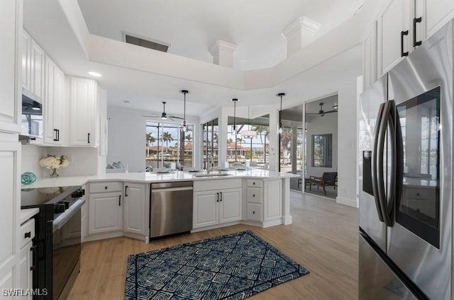 kitchen featuring stainless steel appliances, a peninsula, visible vents, and white cabinetry