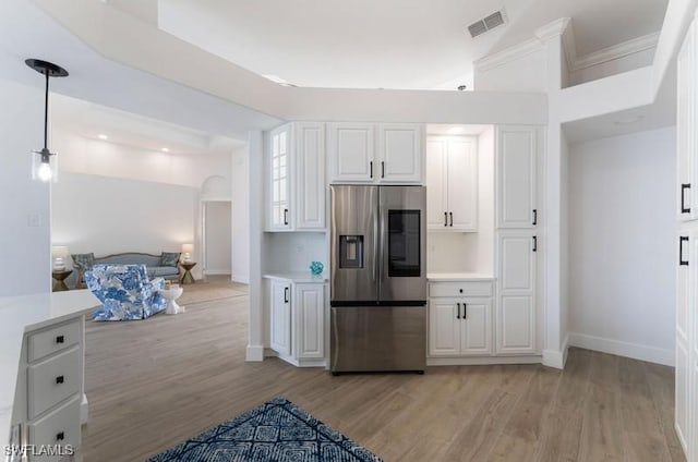 kitchen with visible vents, open floor plan, white cabinets, light wood-type flooring, and stainless steel fridge