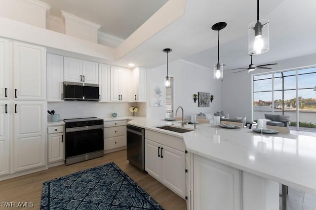 kitchen featuring stainless steel microwave, electric range oven, white cabinetry, a sink, and dishwasher