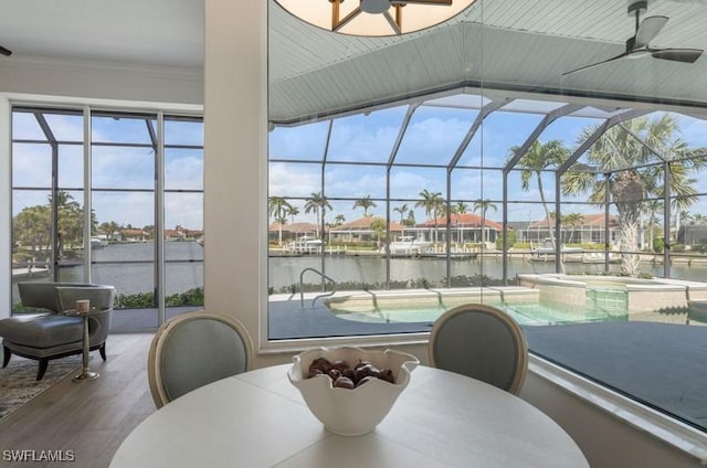 dining space with a water view, a sunroom, crown molding, and a ceiling fan