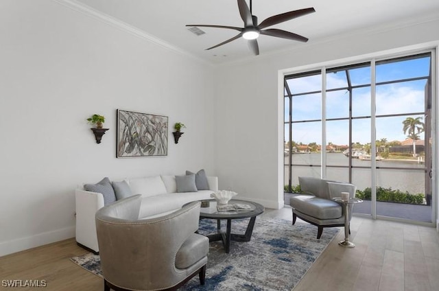 living area featuring baseboards, wood finished floors, a ceiling fan, and crown molding