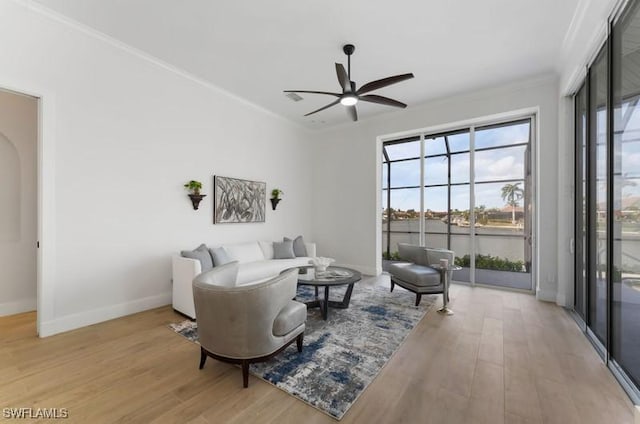 sitting room with light wood-style floors, baseboards, and ornamental molding