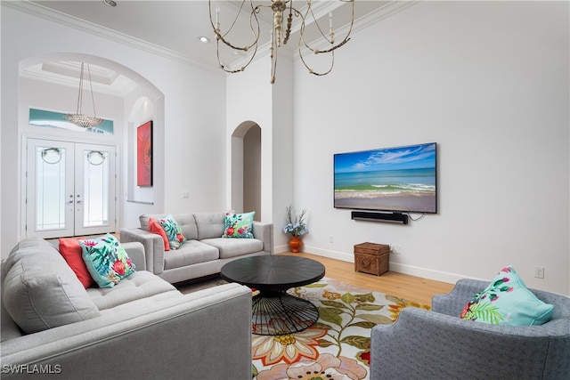 living room featuring ornamental molding, an inviting chandelier, hardwood / wood-style floors, and french doors