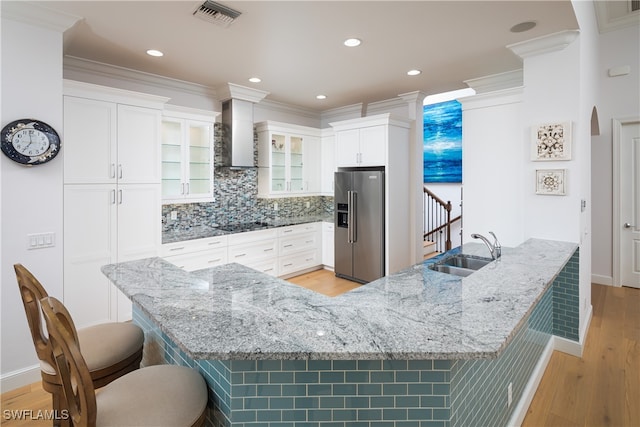 kitchen featuring stainless steel fridge with ice dispenser, a kitchen breakfast bar, white cabinetry, light hardwood / wood-style floors, and sink