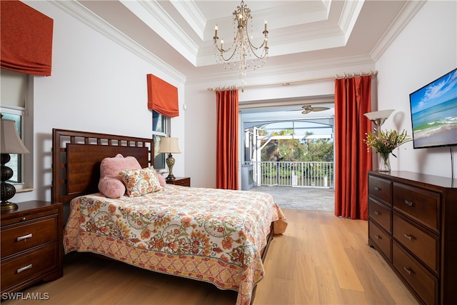 bedroom featuring access to exterior, a tray ceiling, crown molding, a notable chandelier, and light hardwood / wood-style floors