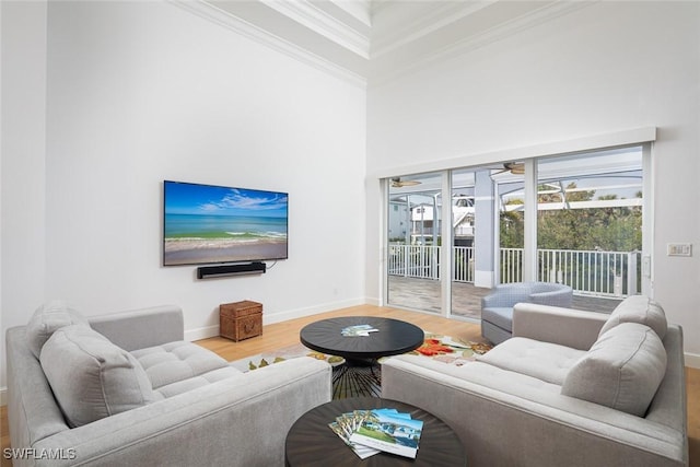 living room featuring baseboards, a high ceiling, wood finished floors, and crown molding