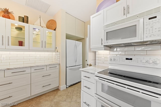 kitchen with white cabinetry, light tile patterned floors, and white appliances